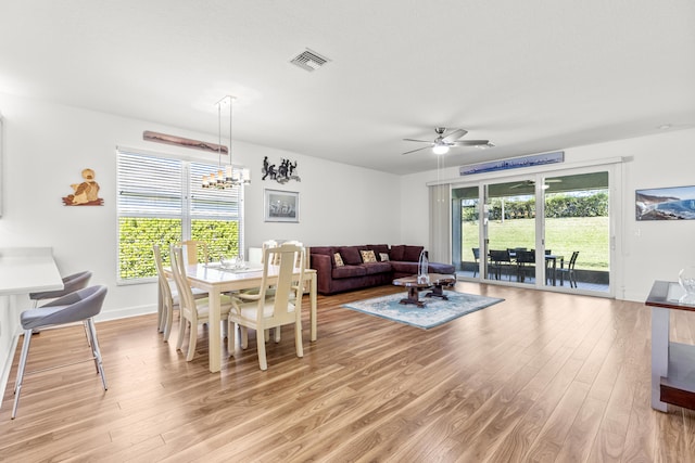 living room featuring ceiling fan with notable chandelier and light wood-type flooring