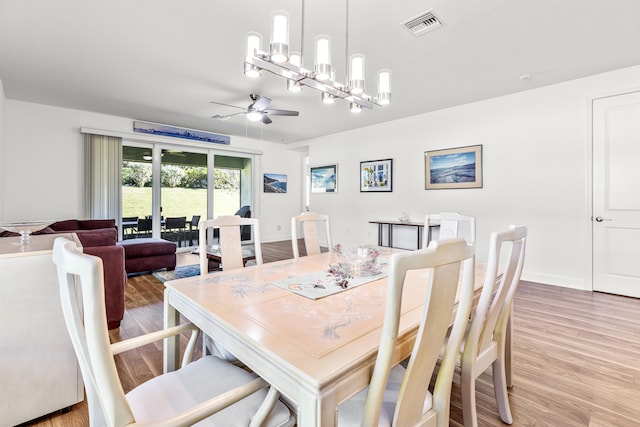 dining area with wood-type flooring and ceiling fan with notable chandelier