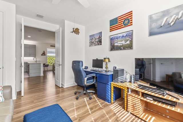 office with hardwood / wood-style floors, a textured ceiling, and sink