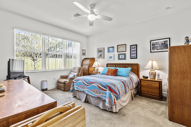 carpeted bedroom featuring ceiling fan and a textured ceiling