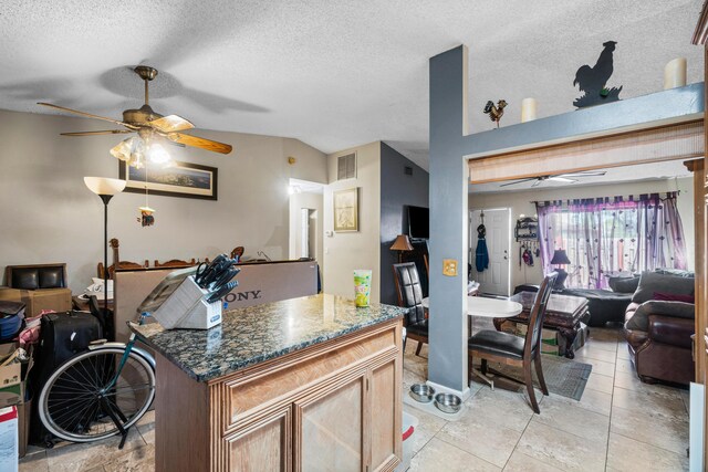 kitchen featuring ceiling fan, light tile patterned floors, a kitchen island, and a textured ceiling