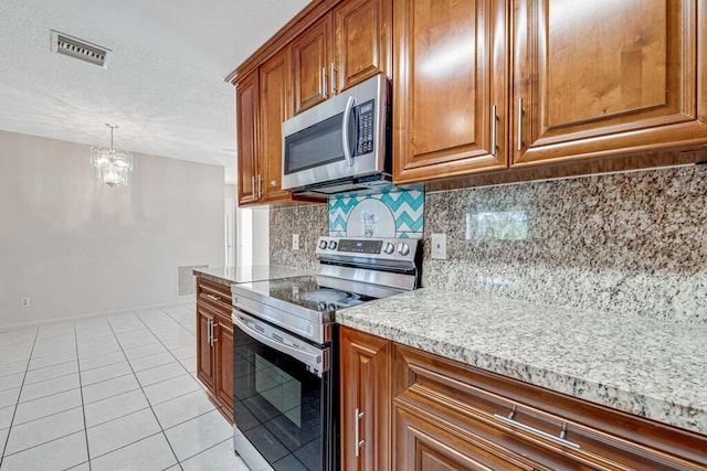 kitchen with backsplash, stainless steel appliances, light tile patterned floors, a chandelier, and hanging light fixtures