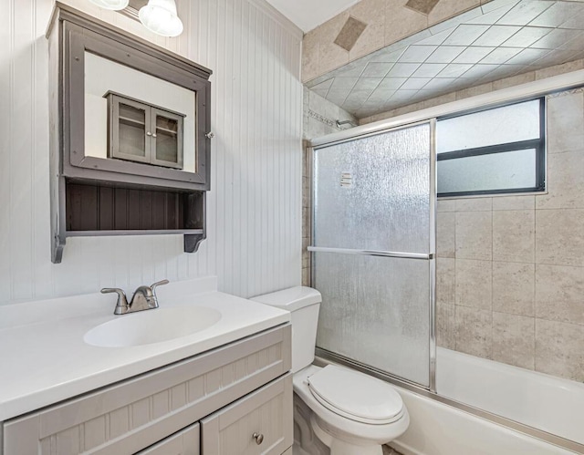 full bathroom featuring vanity, toilet, bath / shower combo with glass door, and wooden walls