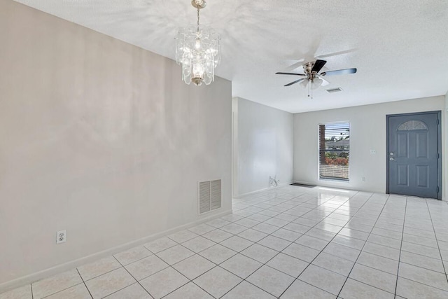 tiled empty room with ceiling fan with notable chandelier and a textured ceiling