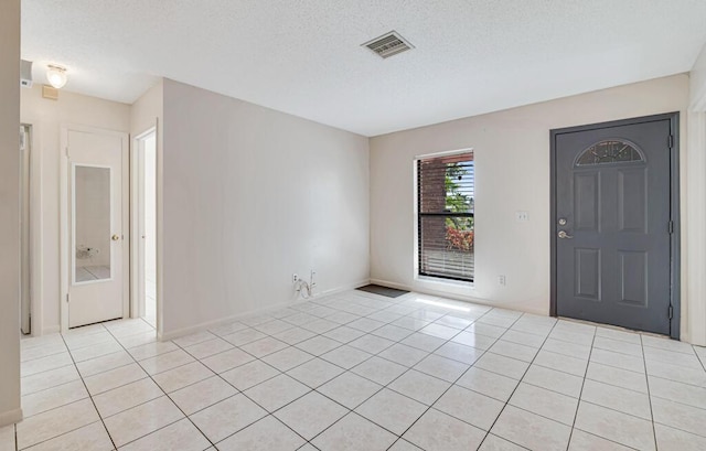 foyer entrance with light tile patterned floors and a textured ceiling