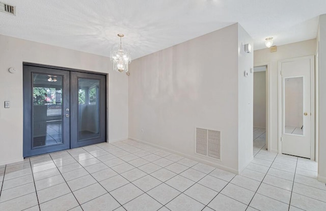 spare room with a chandelier and light tile patterned floors