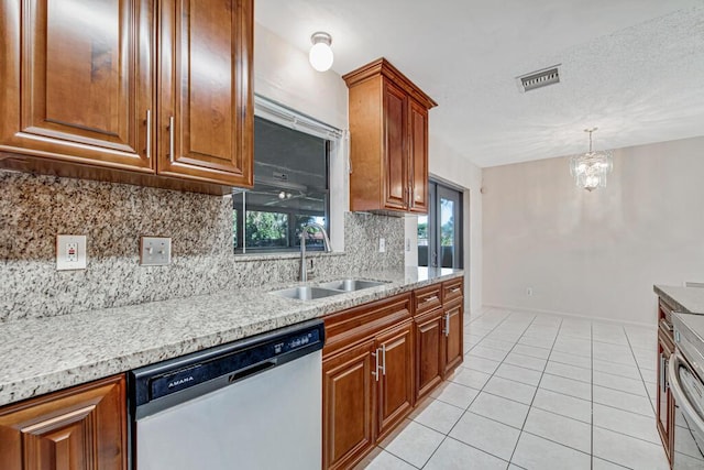 kitchen featuring dishwasher, backsplash, sink, light tile patterned floors, and a chandelier