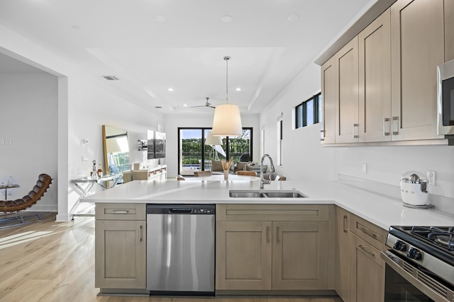 kitchen featuring kitchen peninsula, sink, stainless steel appliances, and light hardwood / wood-style flooring