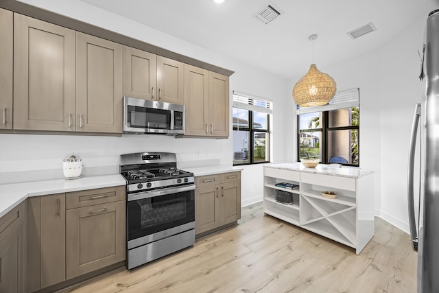 kitchen with appliances with stainless steel finishes, light wood-type flooring, and decorative light fixtures