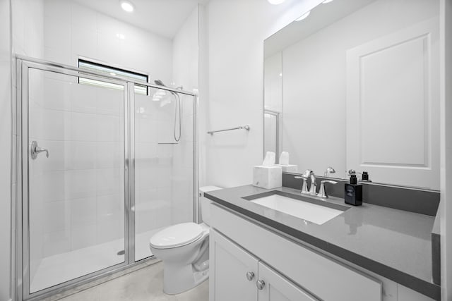 bathroom featuring vanity, a shower with shower door, and toilet