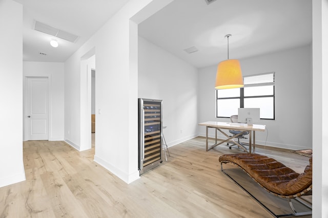 office space featuring wine cooler and light hardwood / wood-style flooring