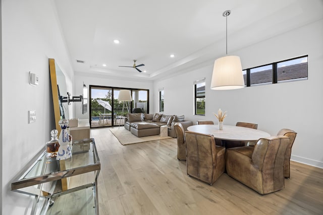 dining area featuring a tray ceiling, ceiling fan, and light hardwood / wood-style floors