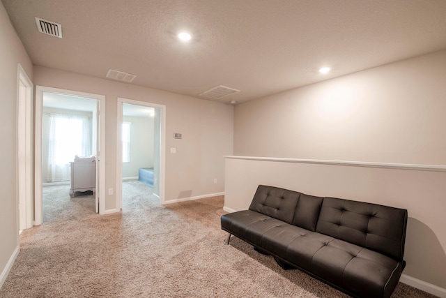 living area with a textured ceiling and light colored carpet