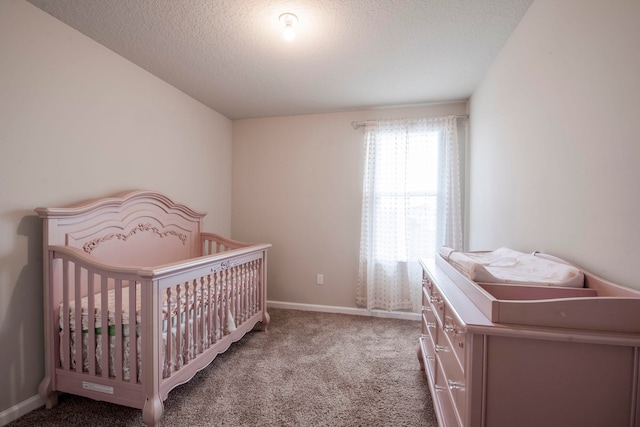 carpeted bedroom featuring a crib and a textured ceiling