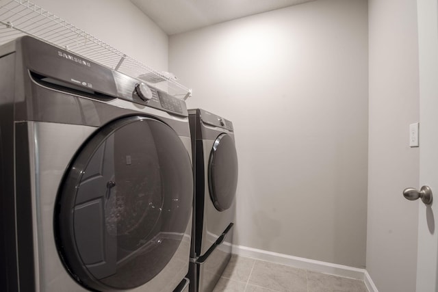 6341 Topsail Dr, West Palm Beach, FL 33413 - laundry room with washer and clothes dryer, light tile patterned floors, and baseboards