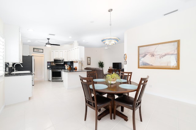 tiled dining room featuring ceiling fan and sink