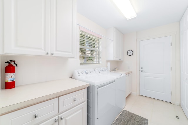 clothes washing area with cabinets, light tile patterned floors, sink, and washing machine and clothes dryer