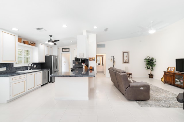 kitchen with appliances with stainless steel finishes, light tile patterned floors, white cabinetry, and lofted ceiling