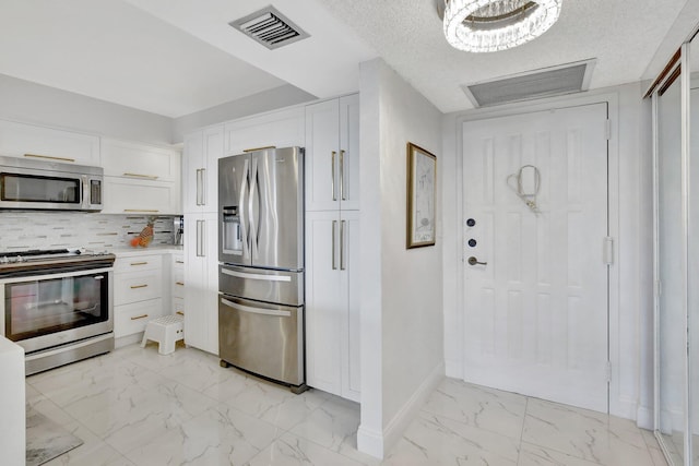 kitchen with white cabinets, backsplash, stainless steel appliances, and a textured ceiling