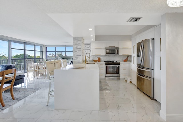 kitchen featuring decorative backsplash, a textured ceiling, stainless steel appliances, sink, and white cabinetry