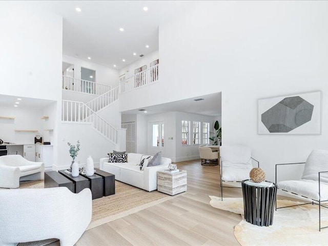 living room featuring a towering ceiling and light hardwood / wood-style flooring