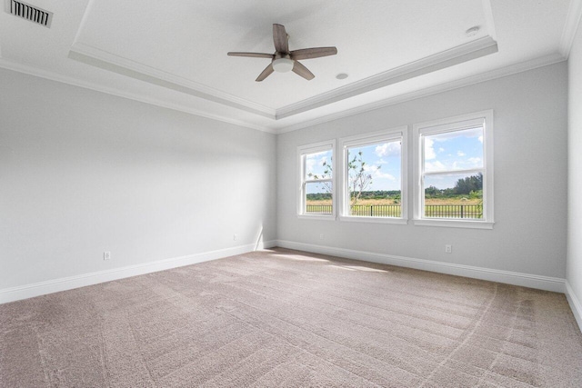 empty room with carpet flooring, ceiling fan, ornamental molding, and a tray ceiling