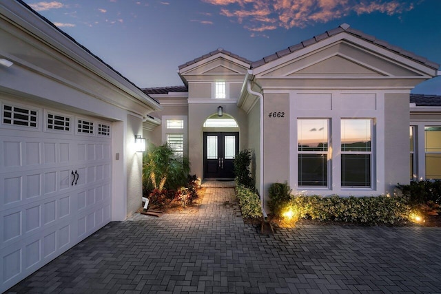 exterior entry at dusk with a garage and french doors