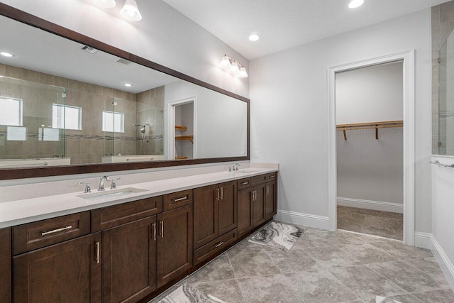 bathroom with tile patterned floors, vanity, tiled shower, and a textured ceiling