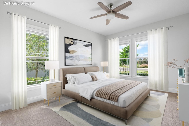 bedroom featuring ceiling fan, light carpet, and multiple windows