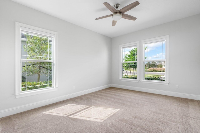 carpeted empty room with a wealth of natural light and ceiling fan