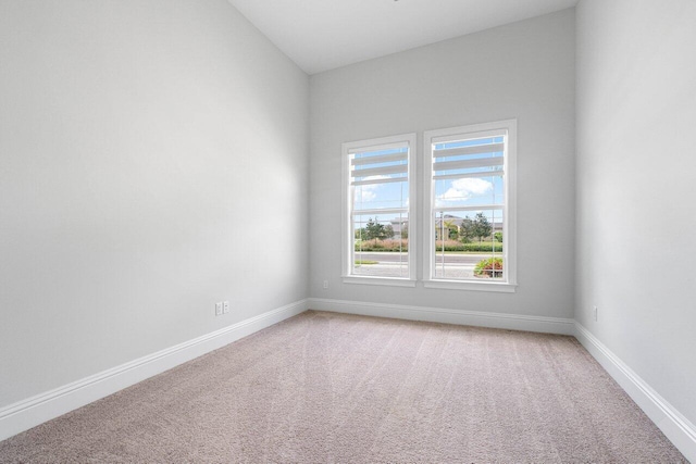 carpeted spare room featuring lofted ceiling