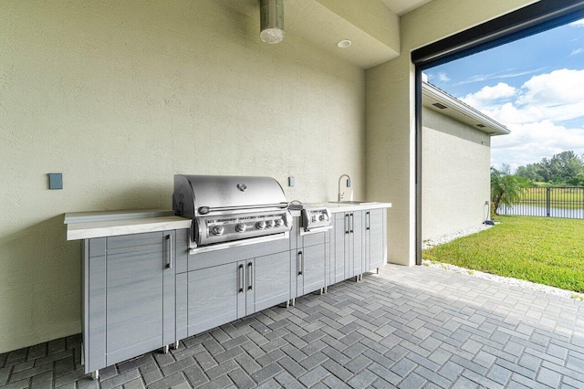 view of patio featuring sink, an outdoor kitchen, a water view, and a grill