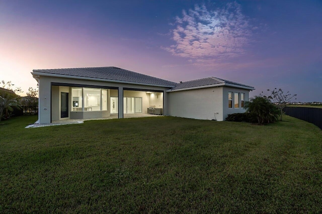 back house at dusk with a lawn