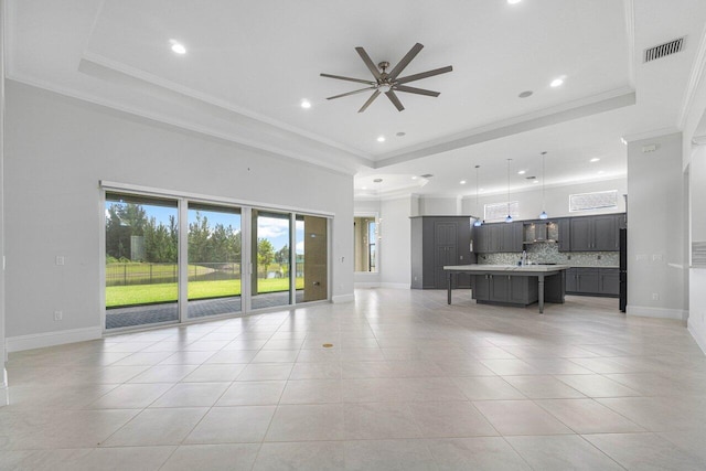 unfurnished living room with ceiling fan, light tile patterned flooring, crown molding, and a tray ceiling