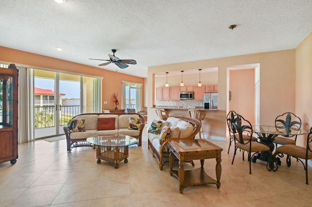 living room with ceiling fan, light tile patterned floors, and a textured ceiling