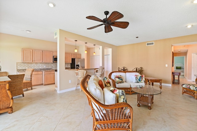 living room with ceiling fan, light tile patterned floors, and a textured ceiling