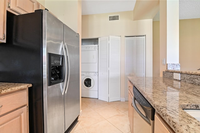 kitchen featuring stacked washer and clothes dryer, appliances with stainless steel finishes, light stone counters, and light brown cabinets