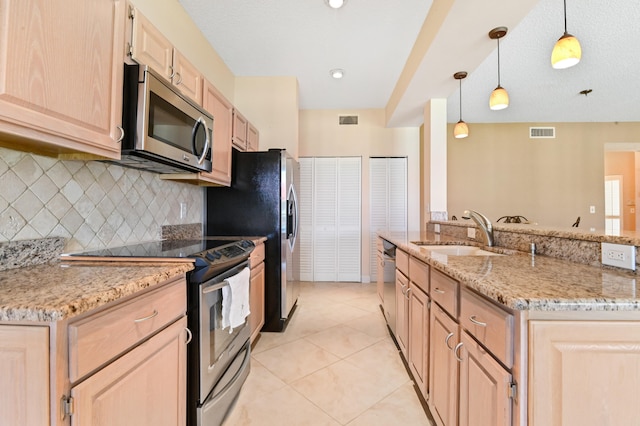 kitchen with sink, stainless steel appliances, pendant lighting, light brown cabinetry, and light tile patterned floors