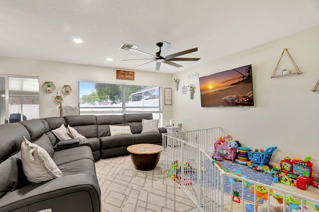 living room with a textured ceiling and ceiling fan