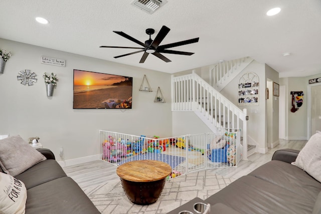 living room with a textured ceiling and ceiling fan