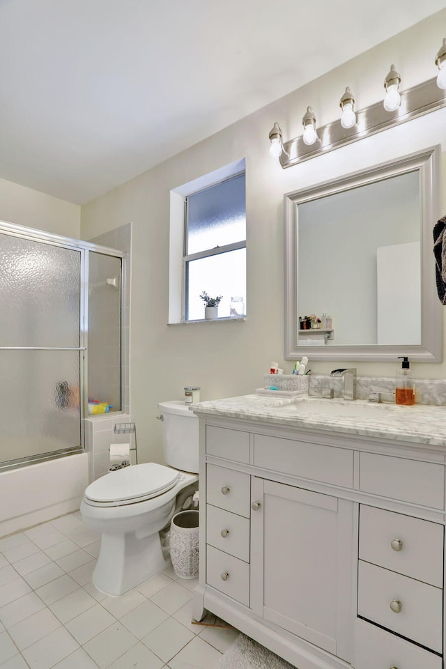 full bathroom featuring toilet, bath / shower combo with glass door, tile patterned flooring, and vanity