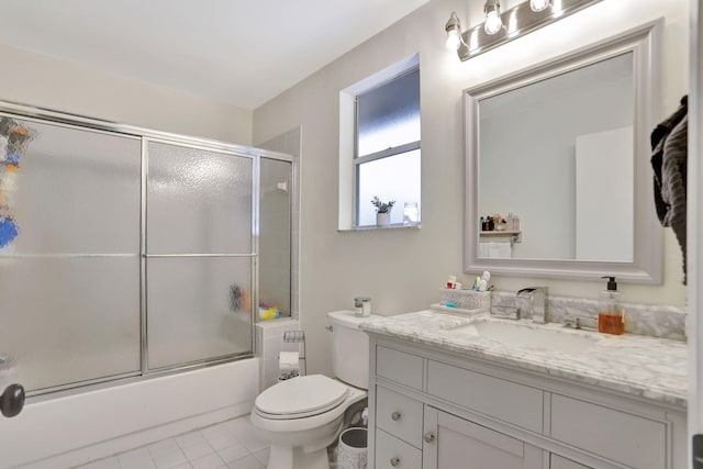 full bathroom with combined bath / shower with glass door, vanity, tile patterned floors, and toilet