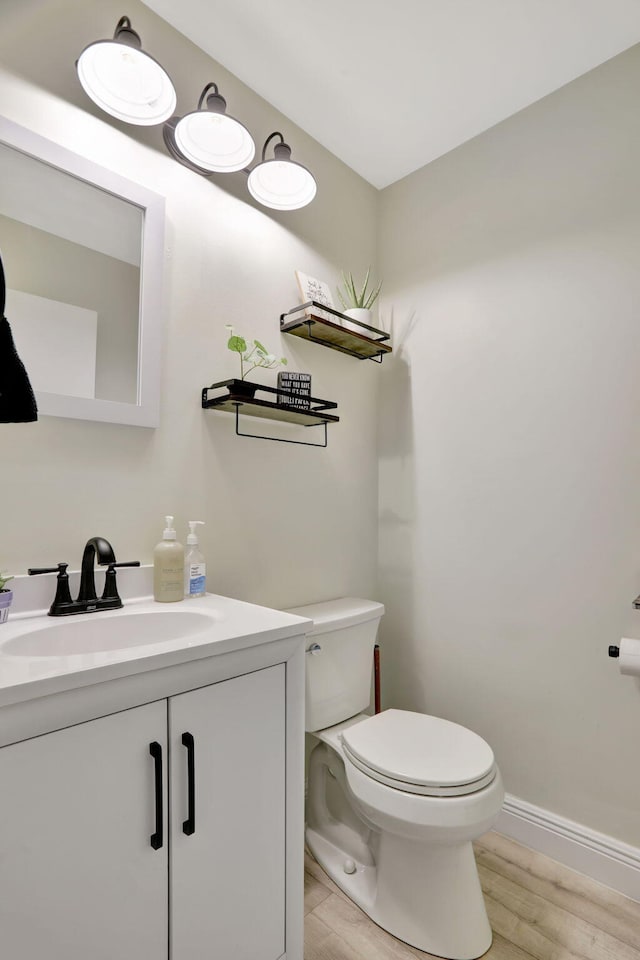 bathroom with hardwood / wood-style flooring, toilet, and vanity