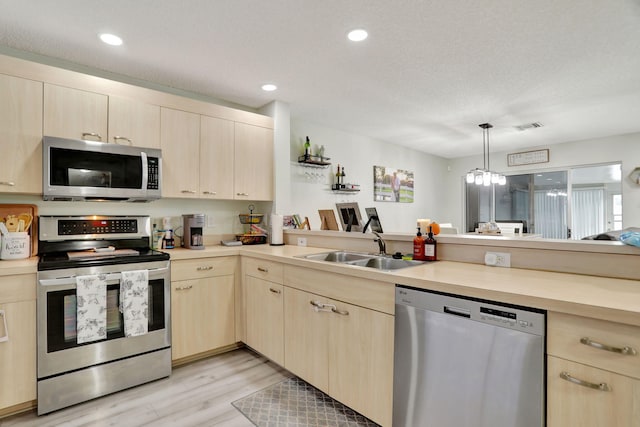 kitchen with decorative light fixtures, light brown cabinets, stainless steel appliances, sink, and a notable chandelier