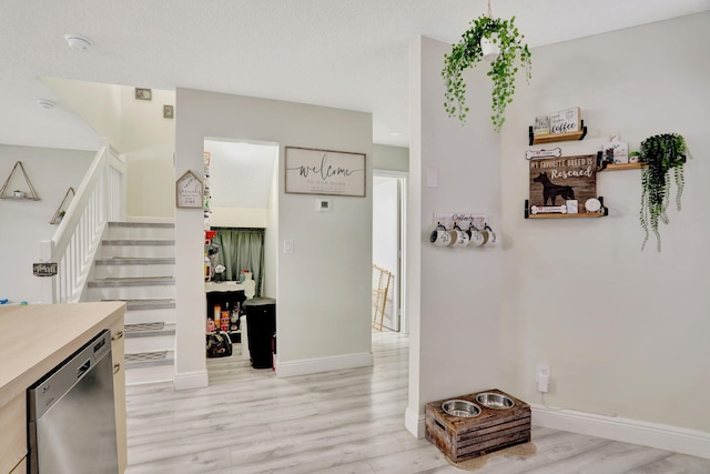 interior space featuring stainless steel dishwasher and light hardwood / wood-style flooring