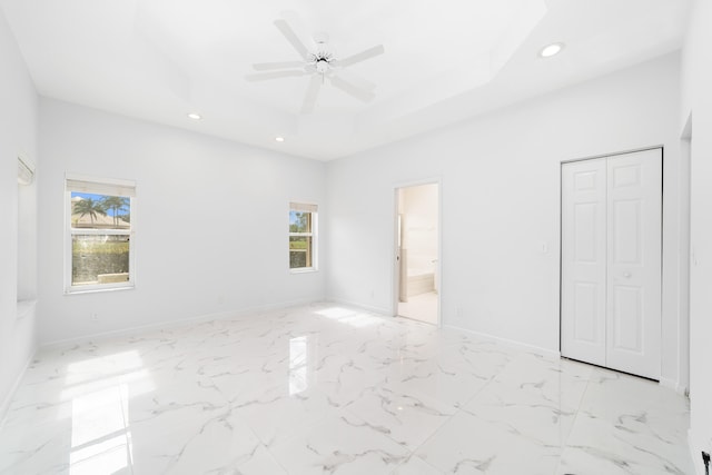 unfurnished bedroom with ceiling fan, a closet, connected bathroom, and multiple windows