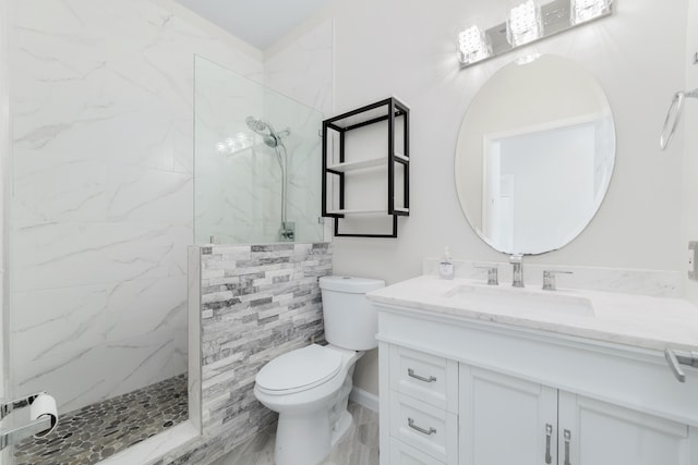 bathroom featuring a tile shower, vanity, and toilet