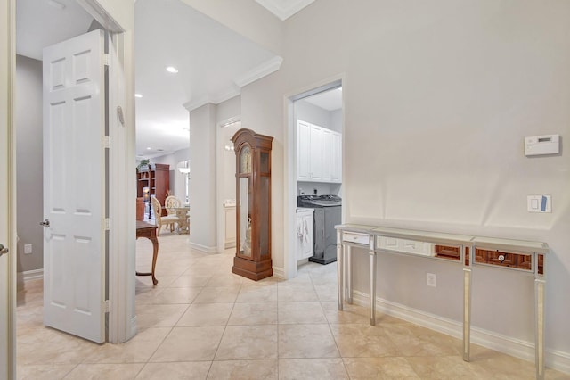 corridor featuring light tile patterned flooring, ornamental molding, and washing machine and clothes dryer