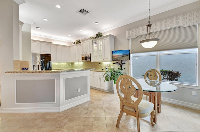 kitchen featuring crown molding, light stone countertops, tasteful backsplash, decorative light fixtures, and stainless steel appliances