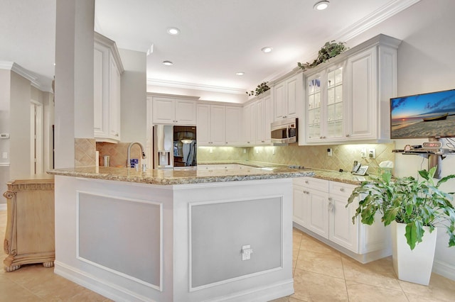 kitchen with decorative backsplash, kitchen peninsula, light stone countertops, refrigerator with ice dispenser, and white cabinetry